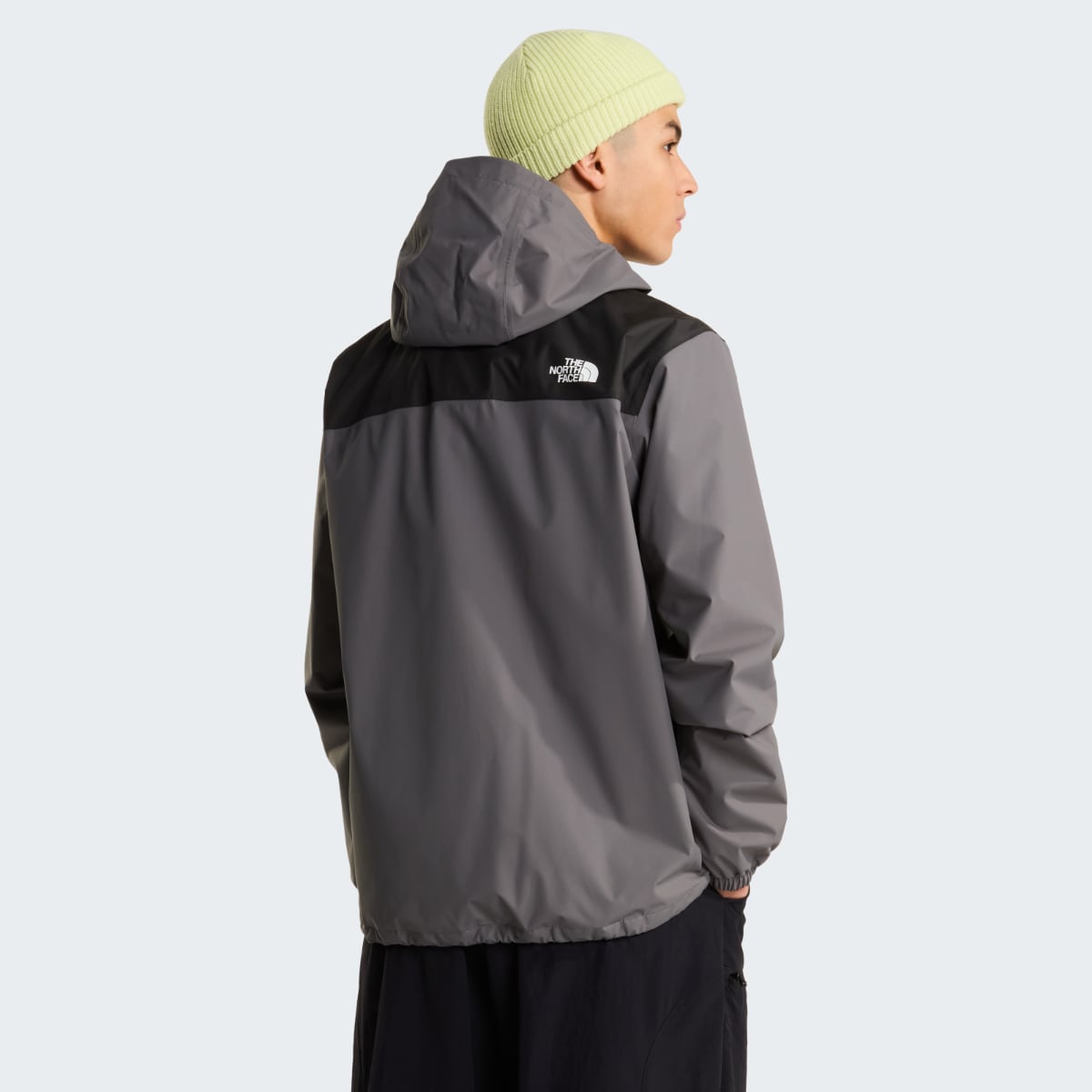Back view of The North Face Antora waterproof jacket worn by a model, gray with a black yoke and hood.