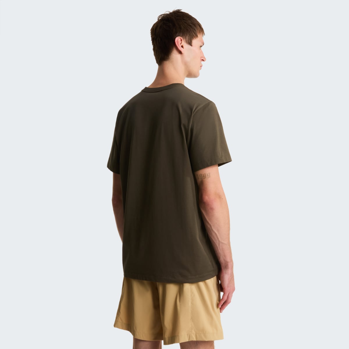 Back view of male model in taupe green short sleeve T shirt with tan shorts