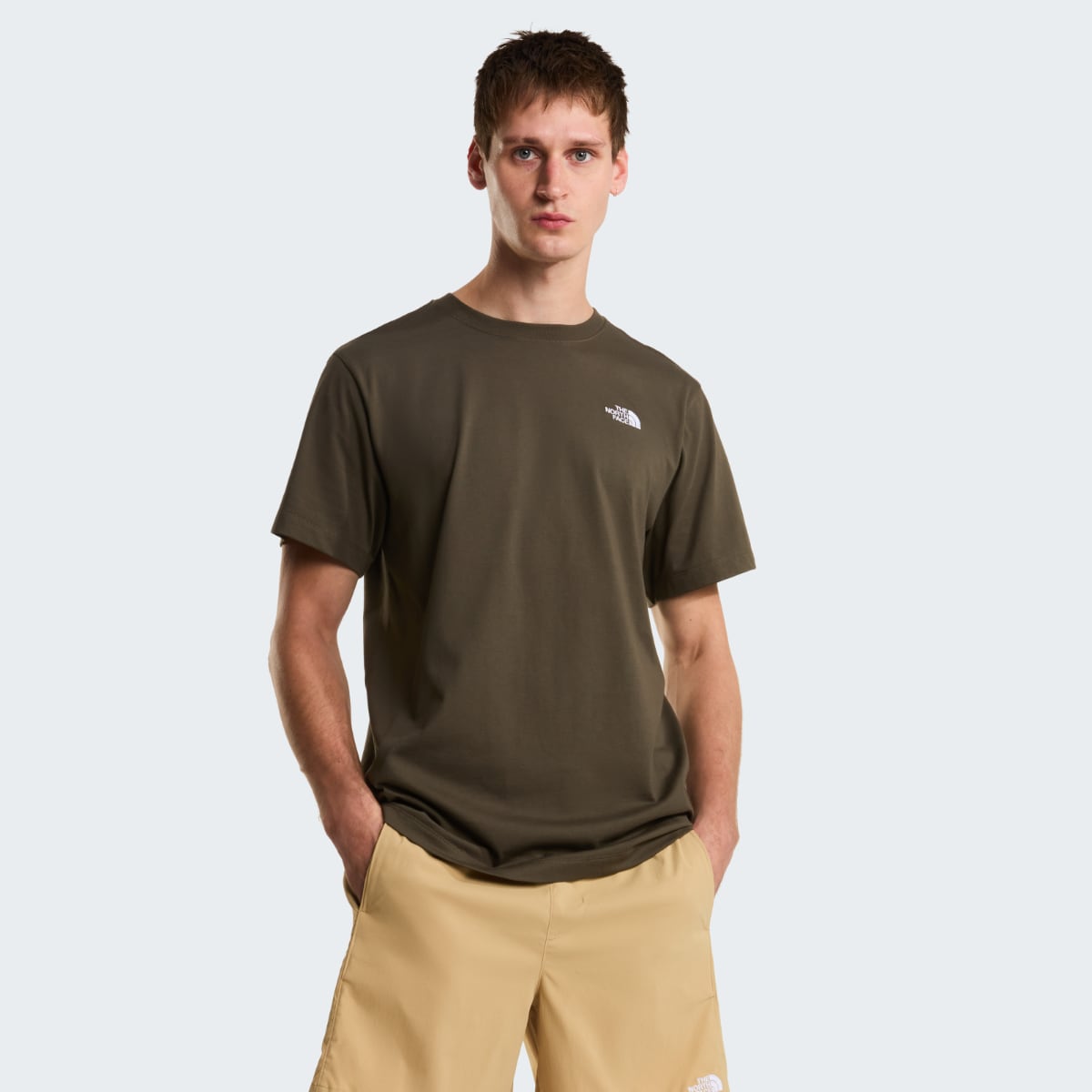 Male model wearing taupe green short sleeve T shirt with small white logo on the chest