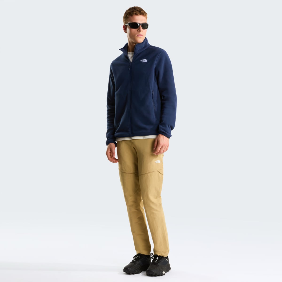Full body shot of a man wearing navy The North Face Glacier fleece jacket with tan pants and black hiking shoes