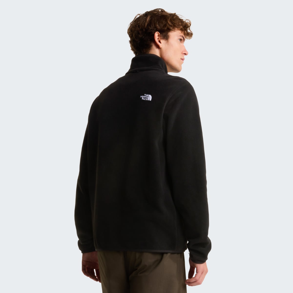 Back view of a male wearing black The North Face Glacier Fleece jacket with logo on the upper back