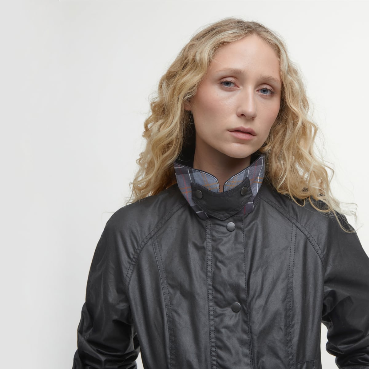 Close up of Barbour Beadnell wax jacket in black on model showing collar and storm flap.