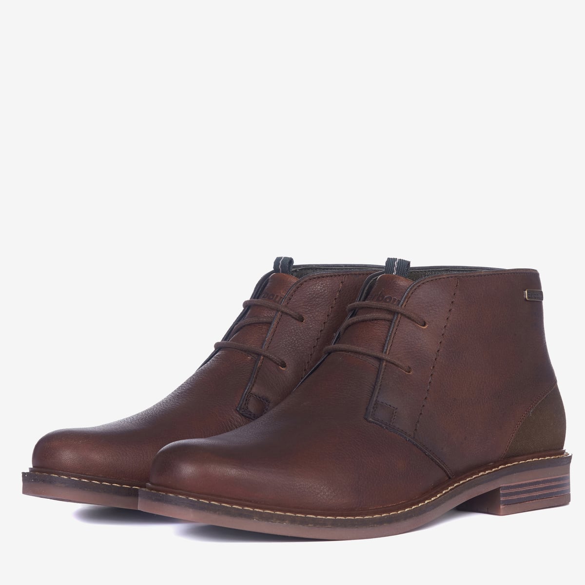 A pair of Barbour Readhead Men's Chukka Boots in teak color, featuring a lace-up closure, with tartan detail on the tongue and a metal Barbour badge.