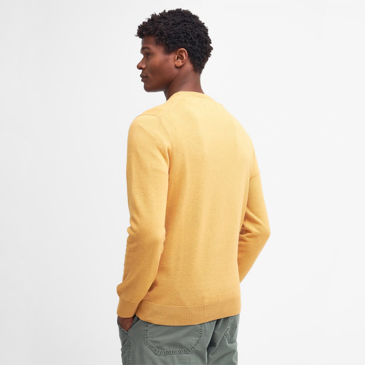 Back view of a male model wearing a honey gold Barbour Pima Cotton crew neck jumper.