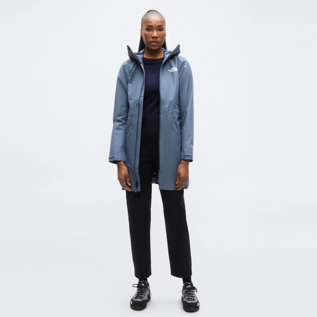Front view of a woman wearing The North Face Hikesteller Parka in granite grey, a knee length waterproof hooded jacket.