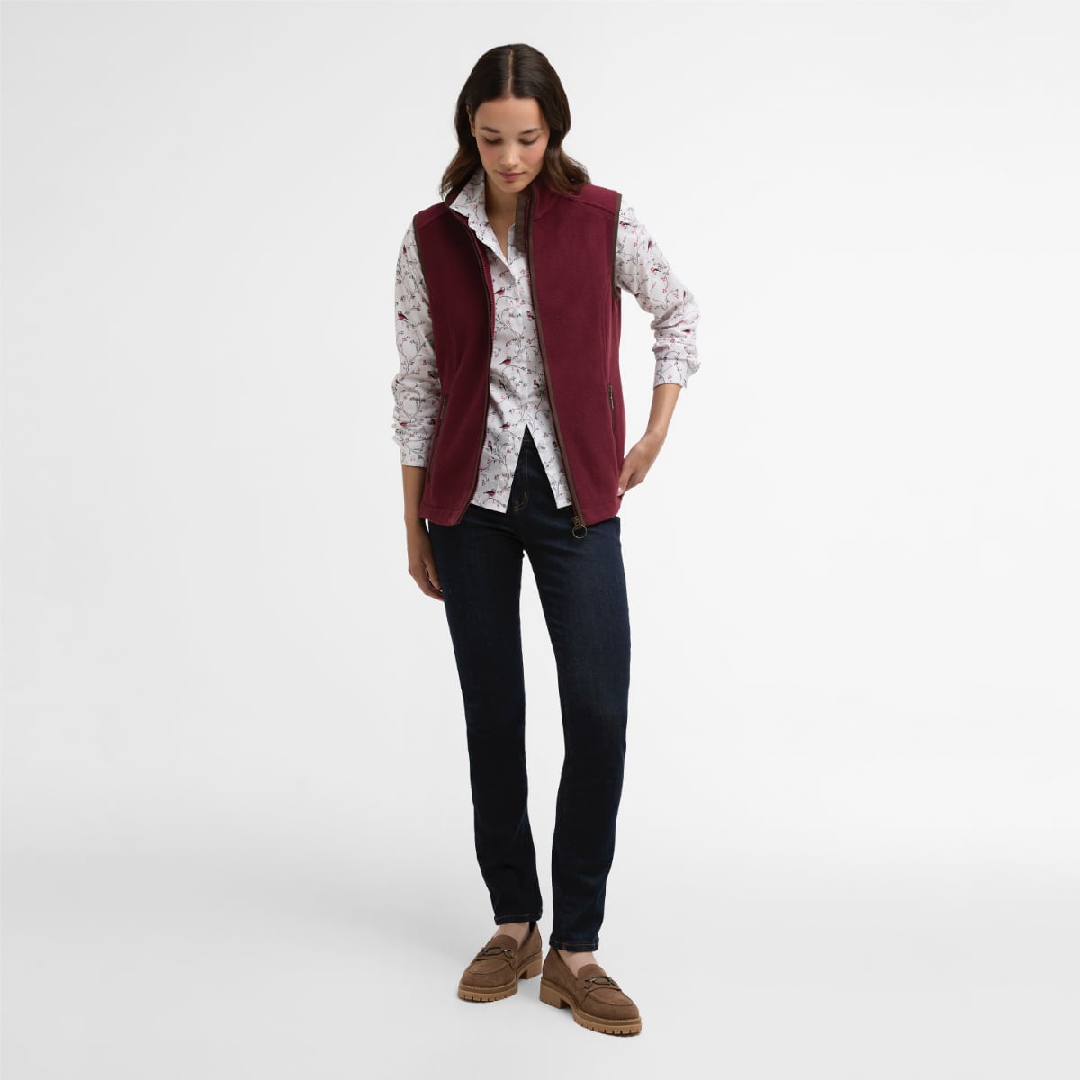 Model wearing Port Barbour Country Colton fleece women's gilet over a floral shirt with dark jeans.