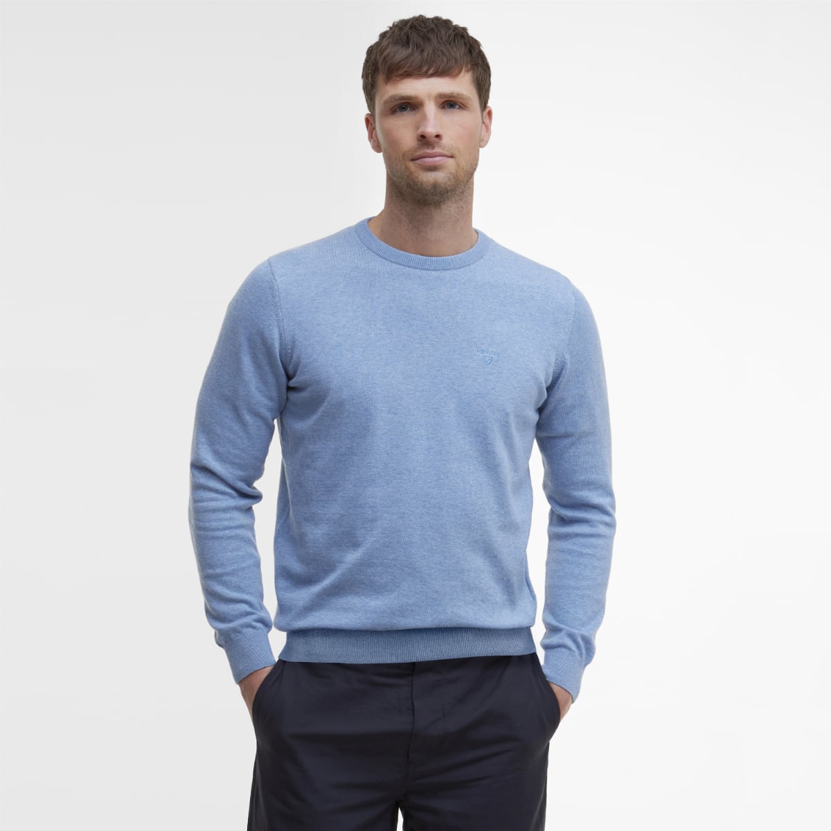 Male model wearing a light blue Barbour Pima Cotton crew neck jumper with hands in pockets