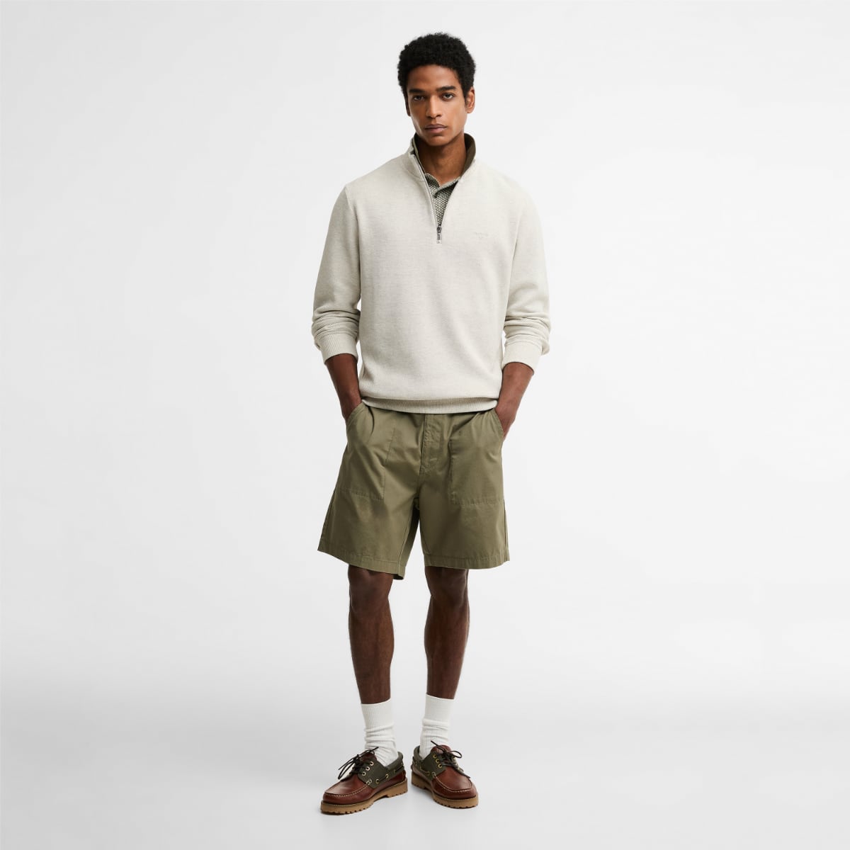 Model wearing Barbour Ravensworth half zip sweatshirt in ecru marl with olive shorts