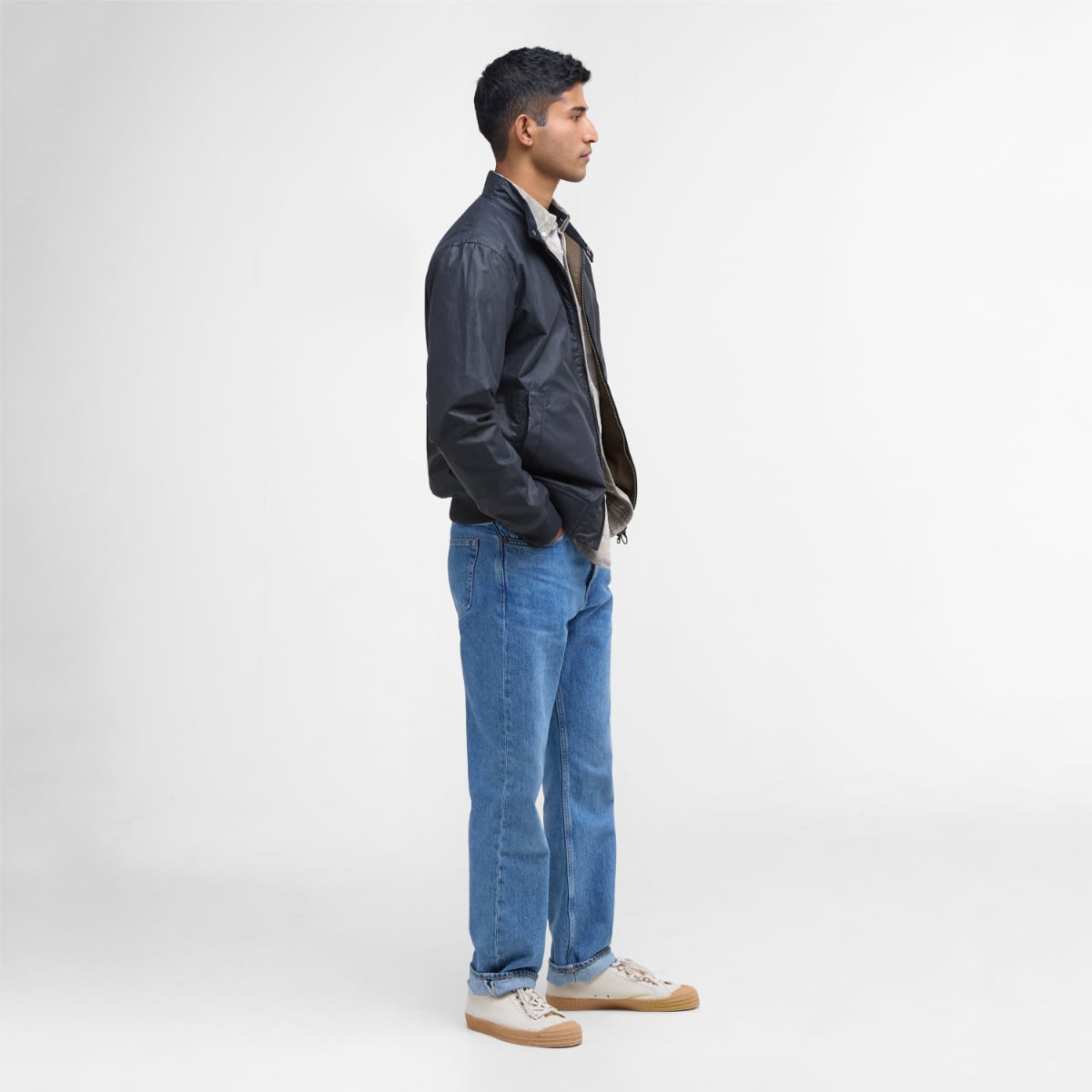 Side profile of a man in a navy Barbour Royston lightweight waxed jacket with light inner layer and jeans