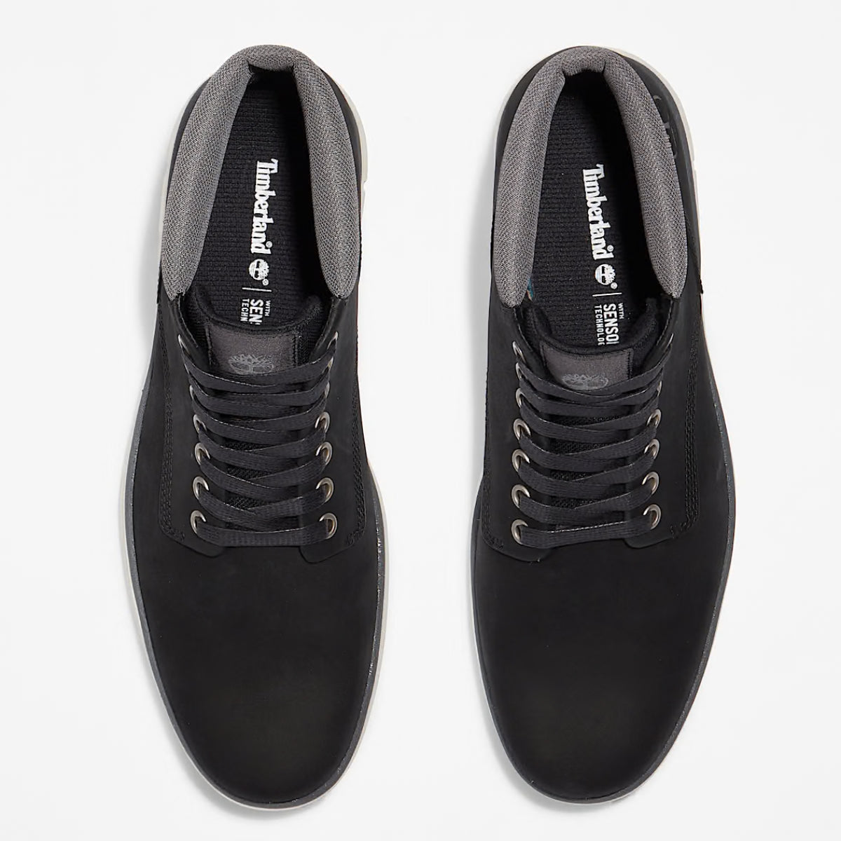 A pair of Timberland Bradstreet Chukka Men's Boots in black color, featuring a low-cut design with eyelets for laces, and a white sole. Top-downview.