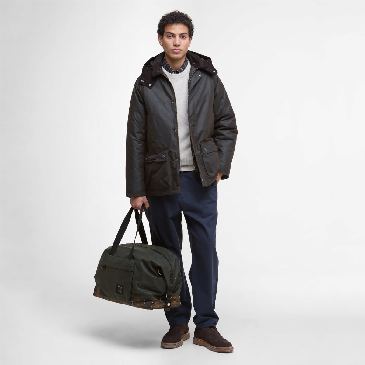 Model carrying Barbour Field Wax Holdall in sage against a neutral backdrop