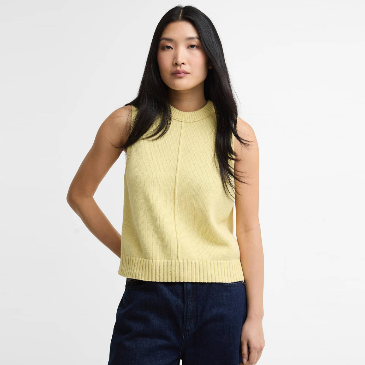 Model wearing Barbour Avon knitted vest in soured citrus a light yellow sleeveless knit with ribbed hem