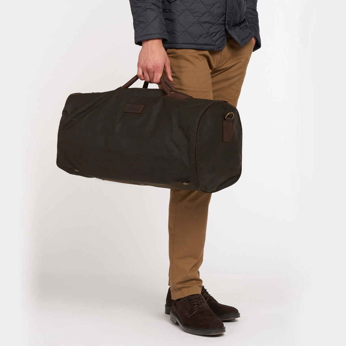 Model carrying Barbour Wax Holdall in countryside setting with shoulder strap