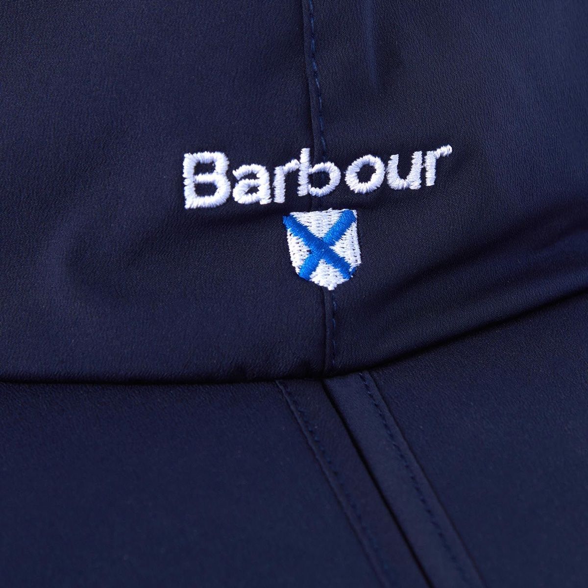 Close-up of navy cap fabric showing white Barbour logo and crest embroidery