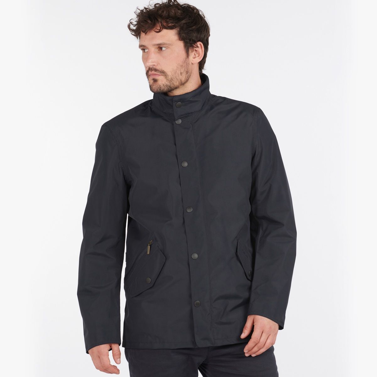 Male model wearing navy Barbour Spoonbill waterproof jacket with stand collar and front snaps.