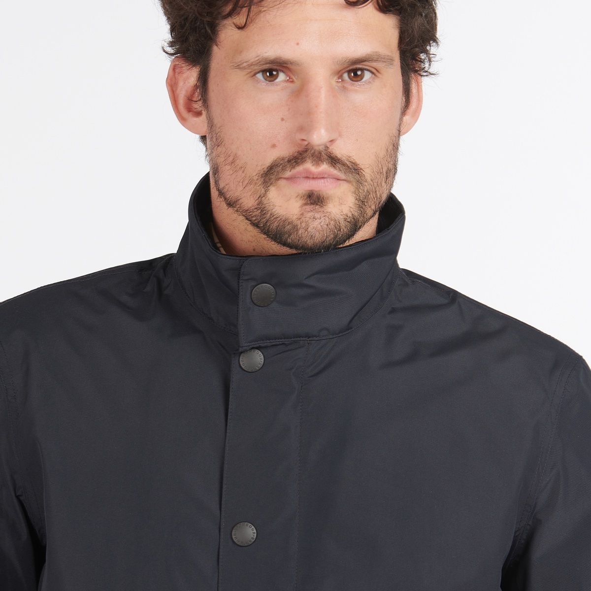 Close up of the navy Barbour Spoonbill jacket showing a high collar and front snap fasteners.