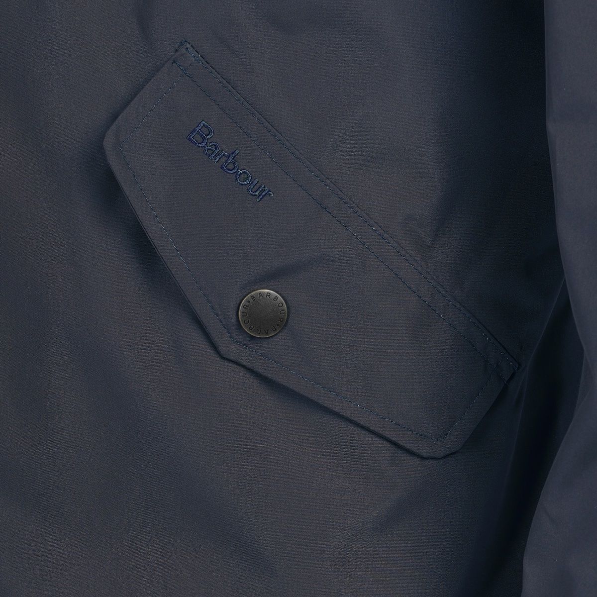 Close-up of navy Spoonbill jacket pocket with embroidered Barbour label and button