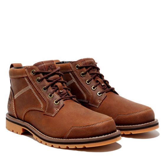 A pair of Timberland Larchmont II Chukka Men's Boots in brown full grain leather with lace up front, padded collar, and rubber cleated outsole.