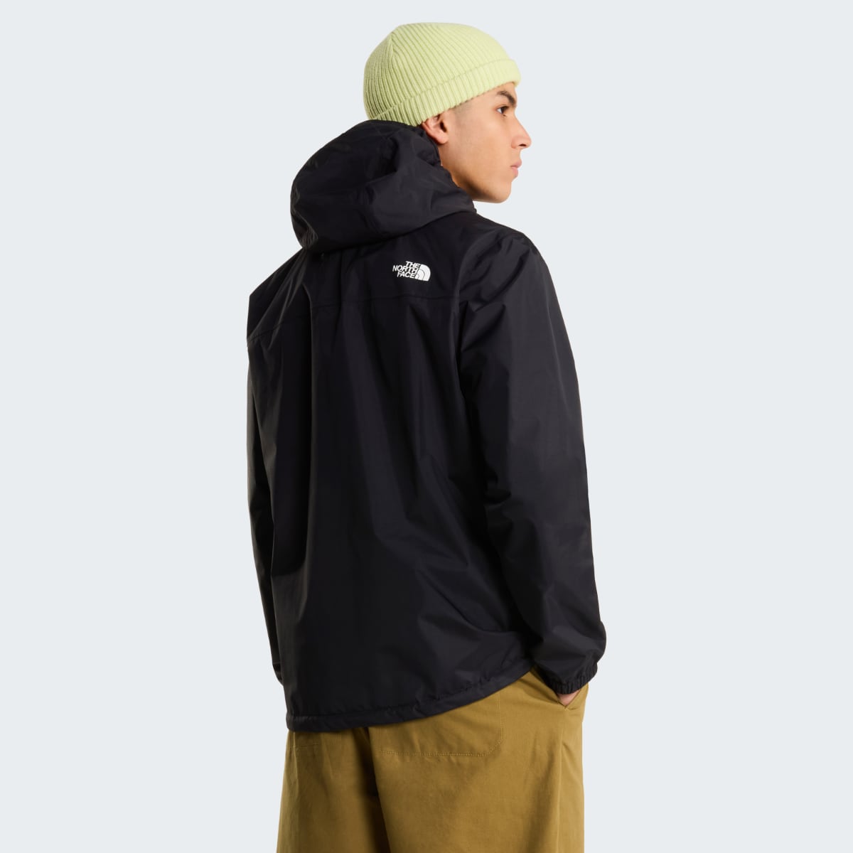 Back view of a man wearing a black The North Face Antora waterproof jacket with hood and a logo on the upper back.