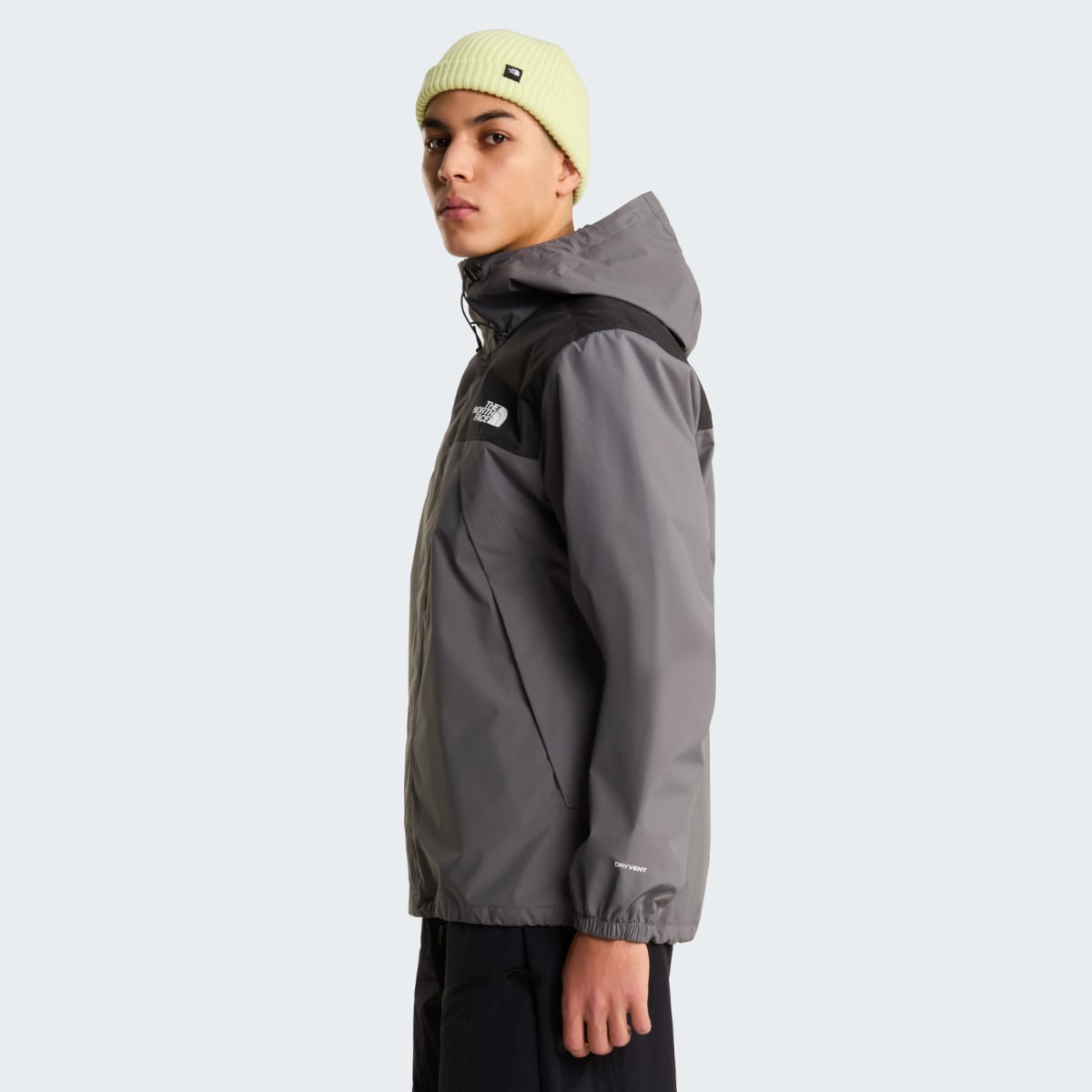 Male model in profile wearing The North Face Antora waterproof jacket in smoked pearl gray with black chest panel.