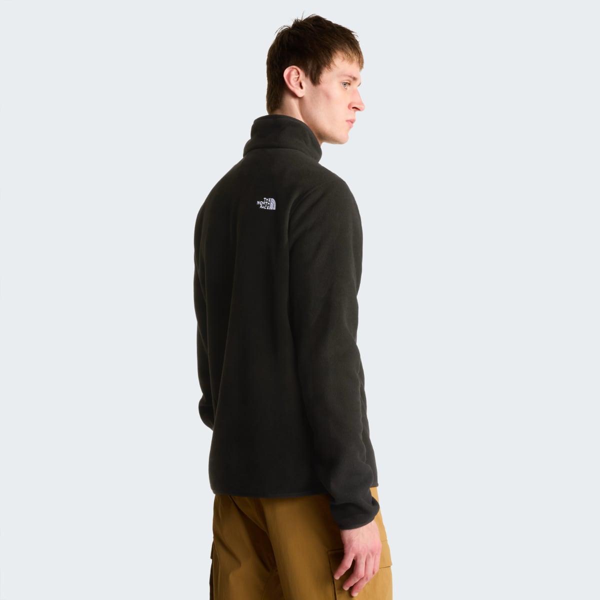 Back view of a male in black The North Face Glacier fleece with logo on the upper back