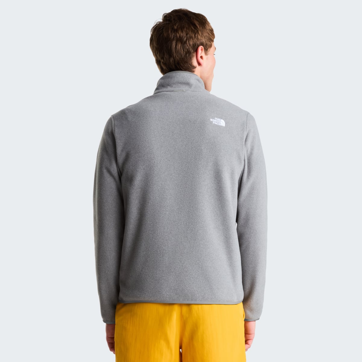 Back view of a grey The North Face Glacier Fleece worn by a model with logo on the upper back.