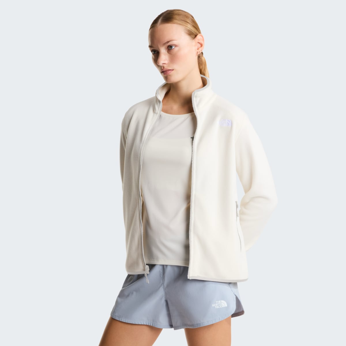 Model wearing The North Face Glacier Fleece Women's Jacket in White Dune with zip front and stand collar angled portrait.