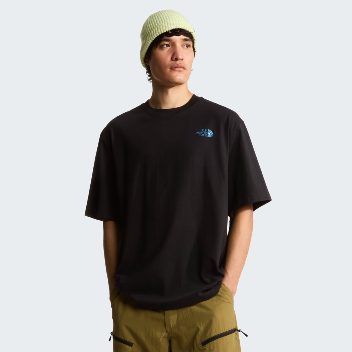Front view of a man wearing a black The North Face Box Liquid oversize short sleeve t shirt with a small blue logo on the chest