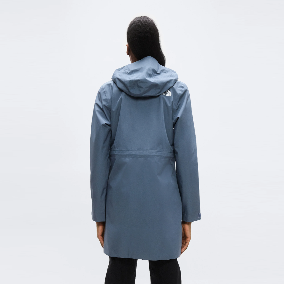 Back view of a woman in granite grey Hikesteller Parka with the hood up, logo on the upper back.