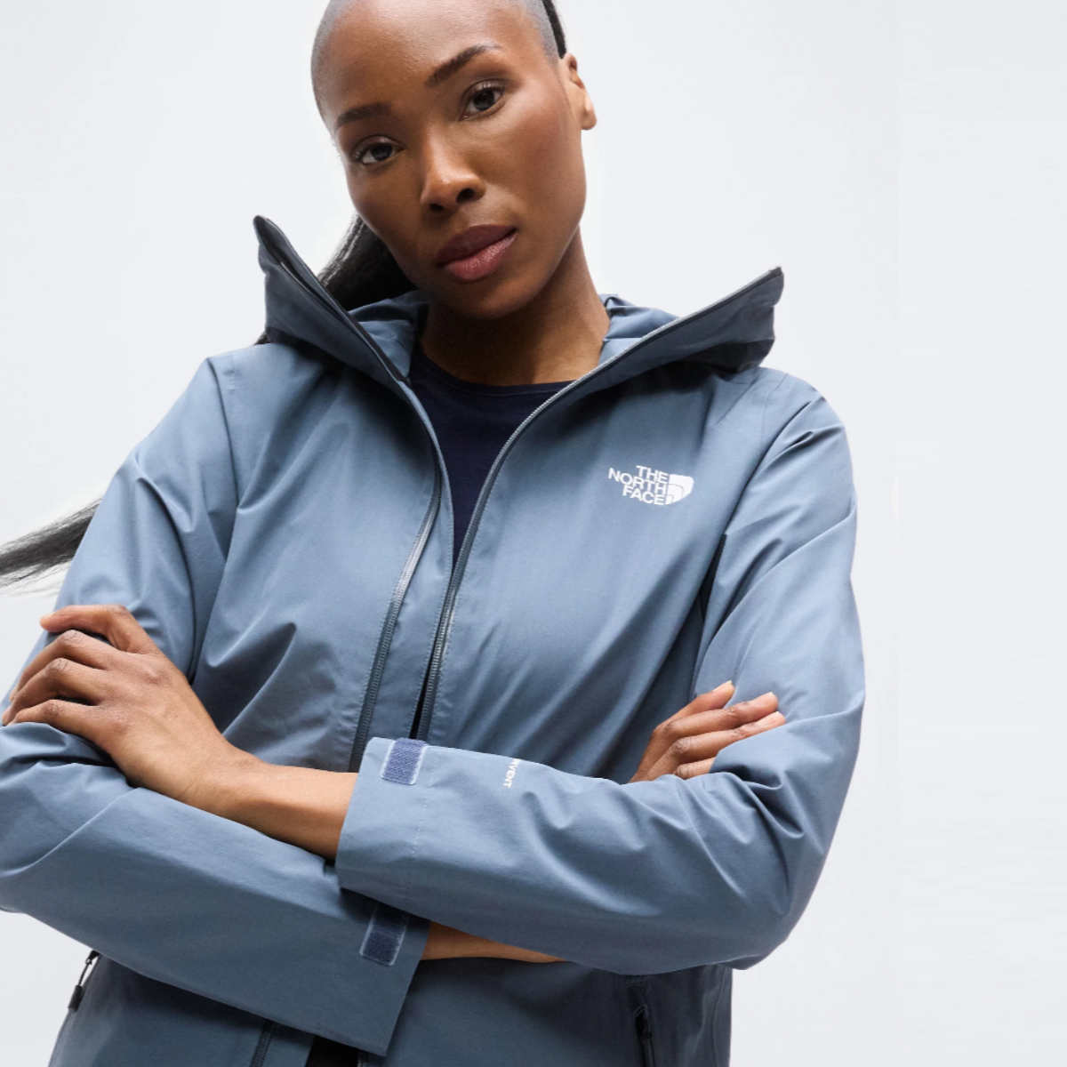 Woman wearing Granite Grey The North Face Hikesteller waterproof parka with hood, arms crossed.