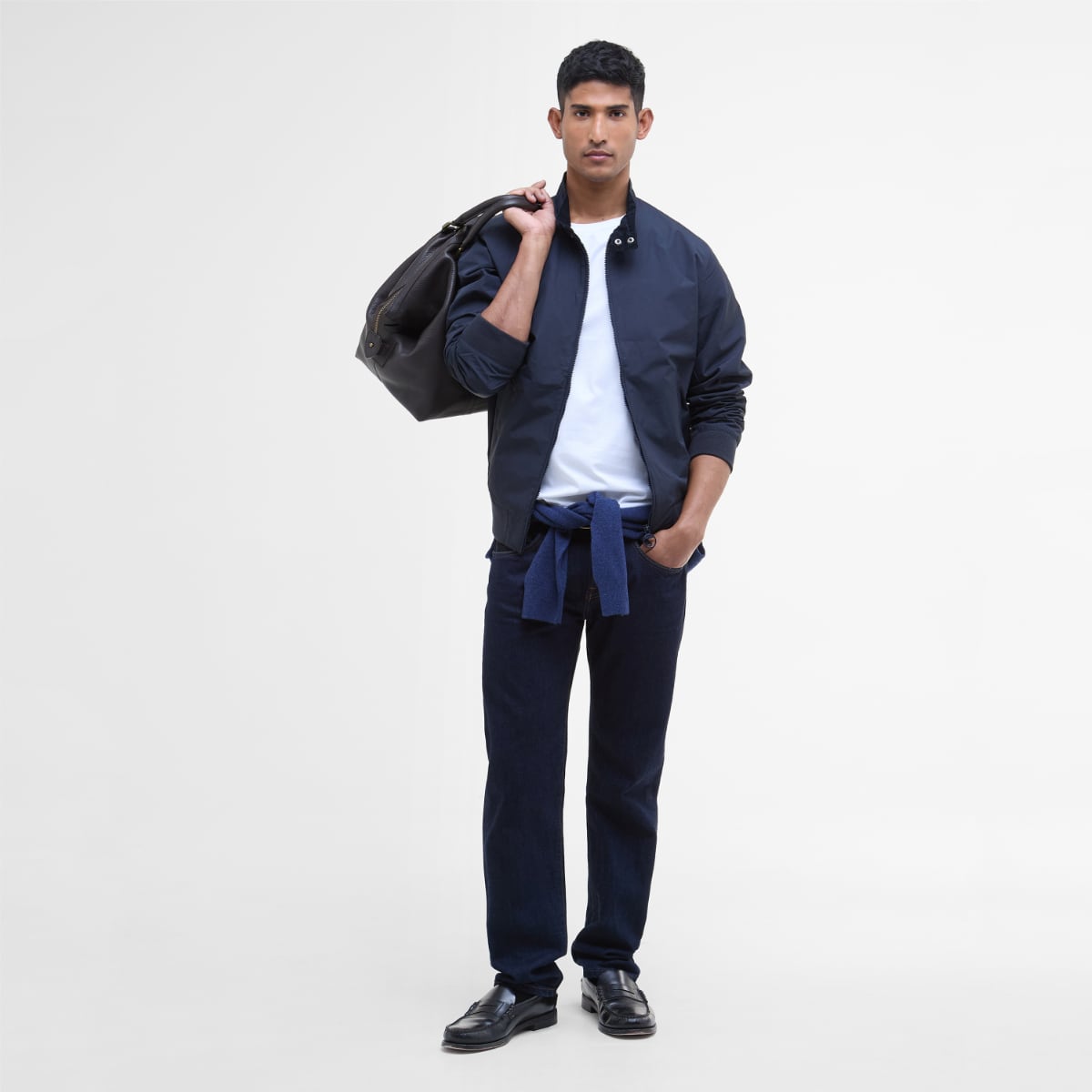 Front view of a male model wearing Barbour Royston navy jacket open over a white tee, carrying a black bag over his shoulder