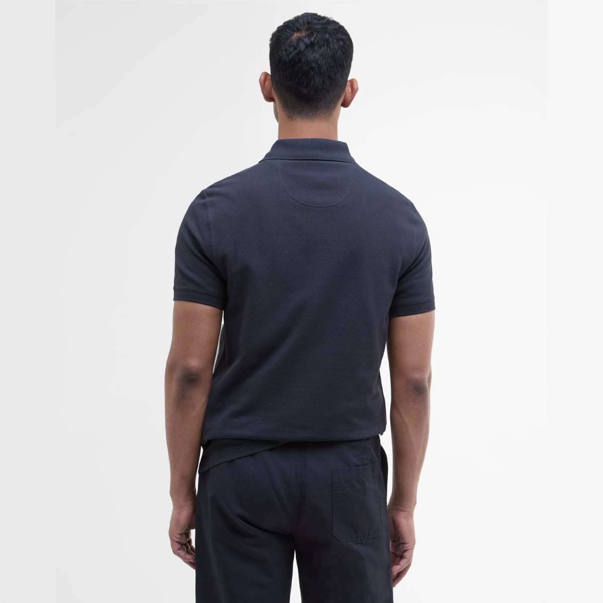 Back view of a navy Barbour Tartan Pique polo shirt worn by a man