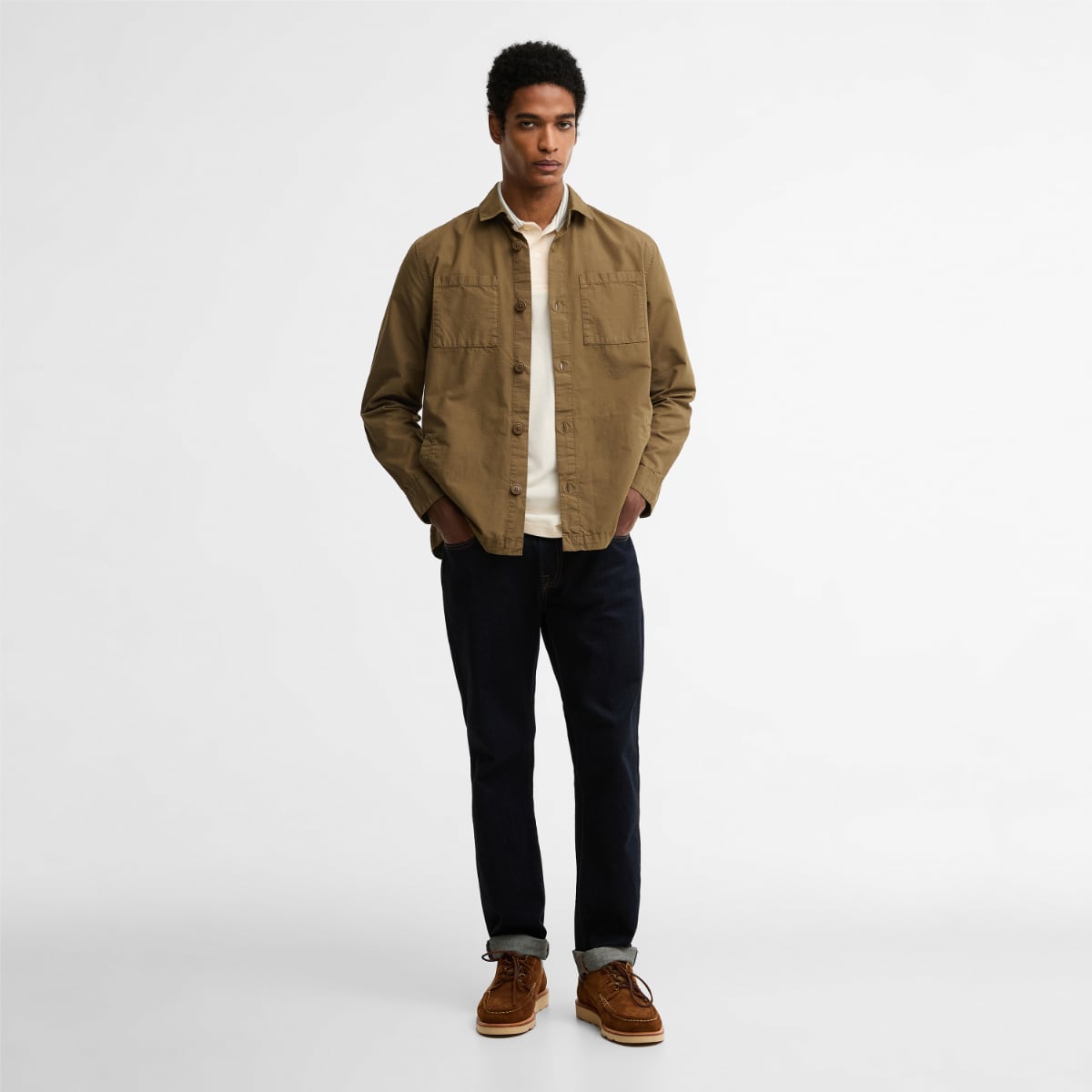Model wearing Barbour Rickfell Ripstop overshirt in clay layered over a light shirt with dark jeans and tan boots