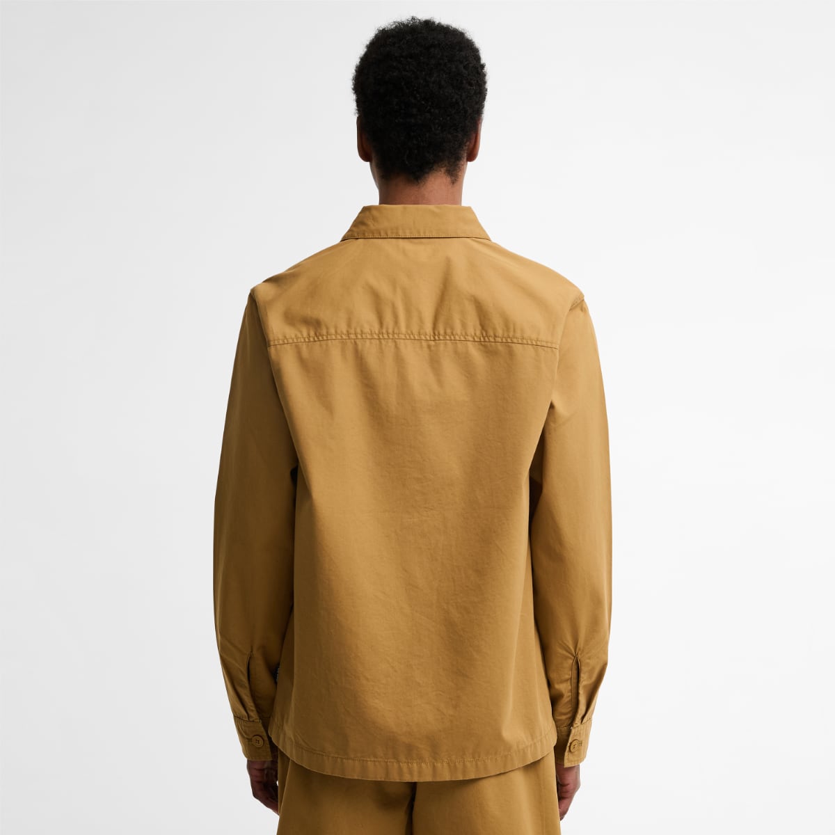 Back view of a model wearing camel Barbour Sherburn overshirt with matching shorts.