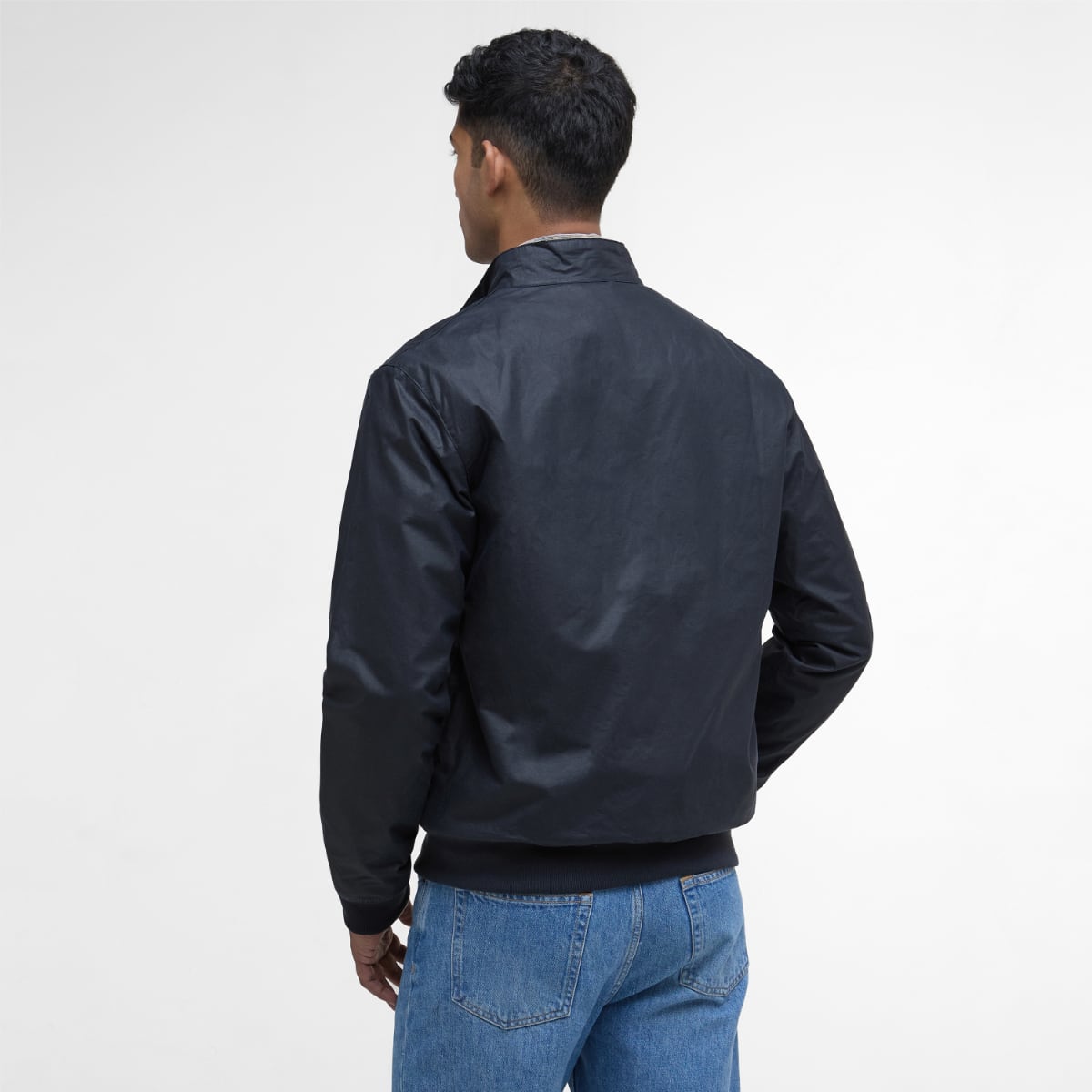 Back view of a navy Barbour Lightweight Royston waxed jacket worn by a man.