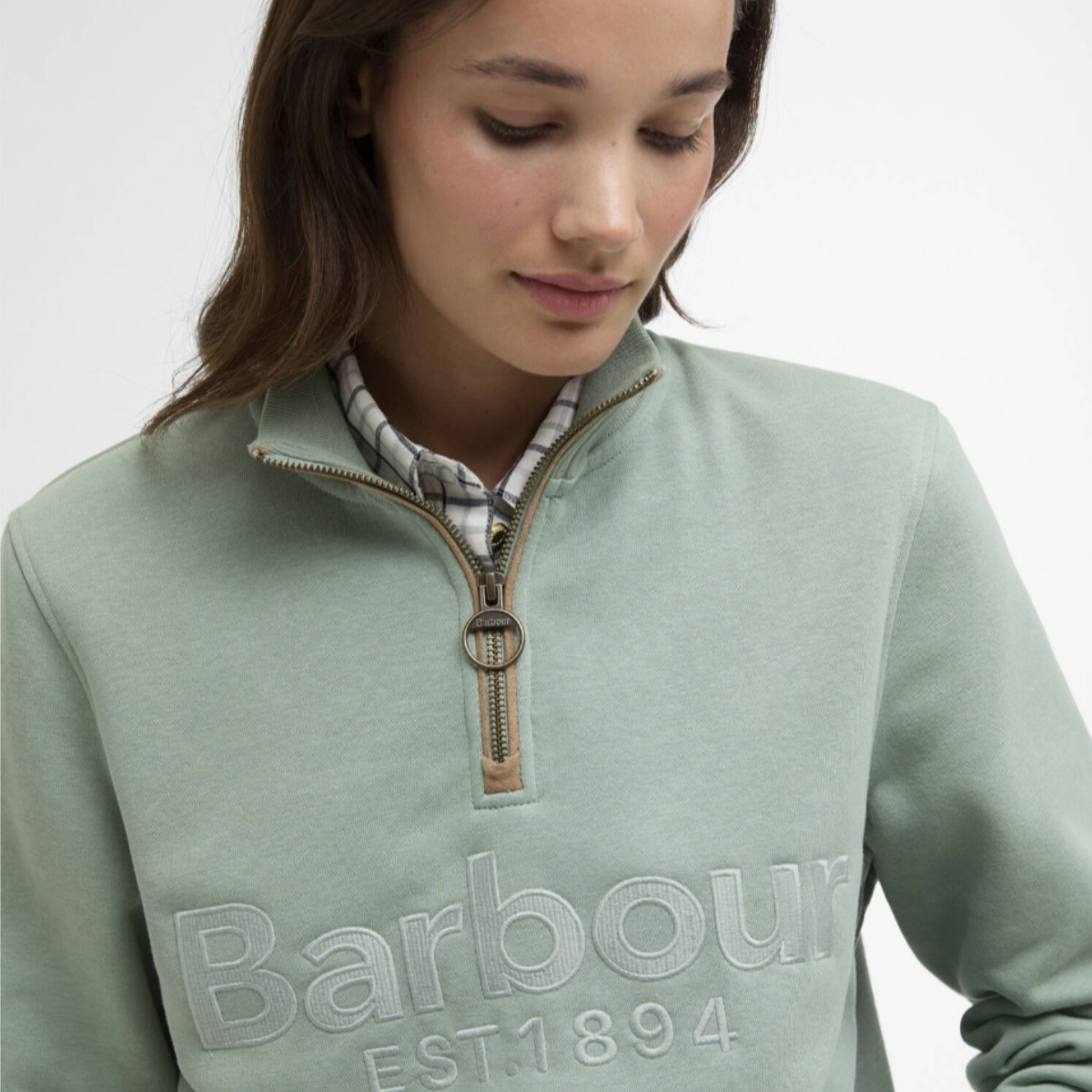 Close up of Barbour Cynthia quarter zip jumper in blue sage with a brass ring zipper pull and embossed Barbour lettering on the chest