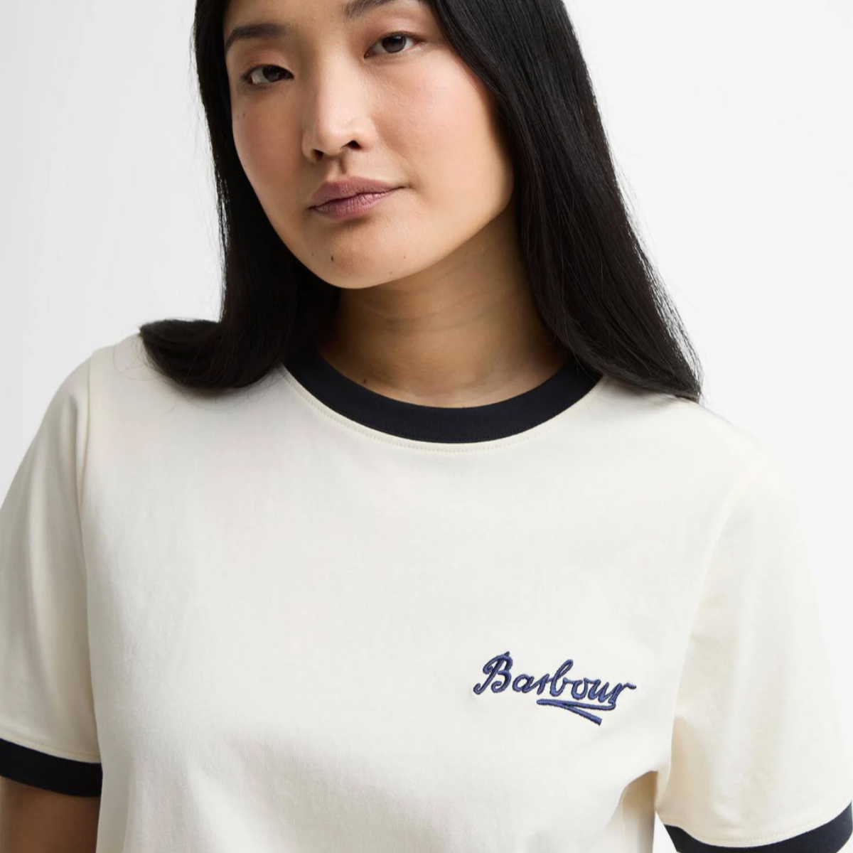 Close up of Barbour Madeline Tipped T Shirt showing cream fabric with black neck trim and Barbour logo on the chest.