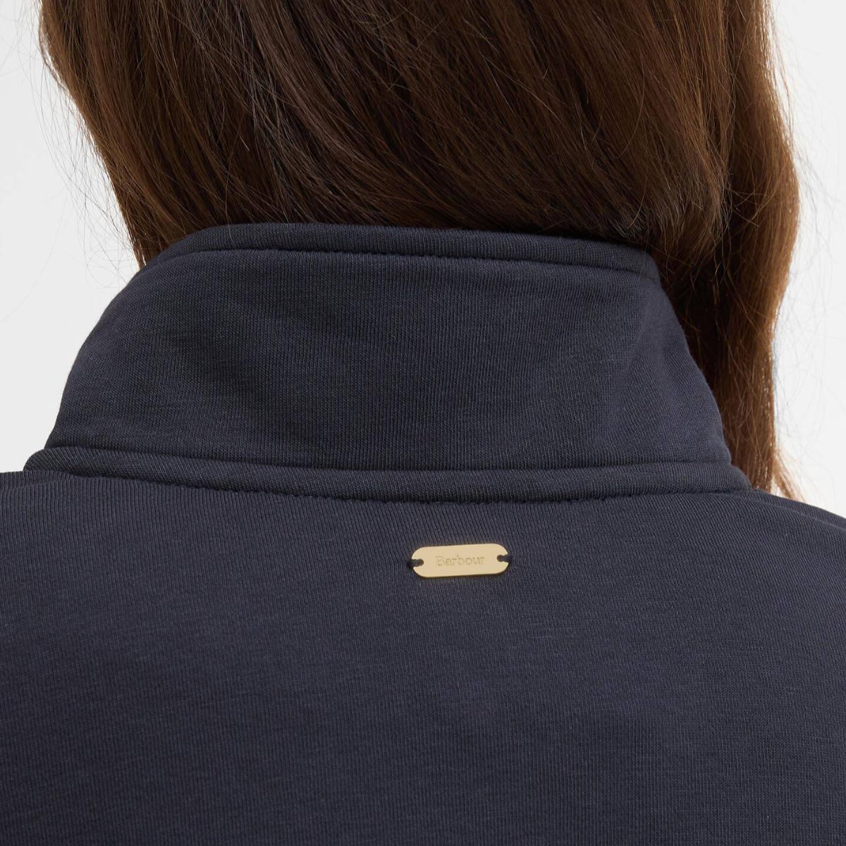 Back view of navy Barbour Zaria jumper showing a small gold metal logo plaque at the collar